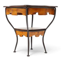 Art Nouveau style occasional table, serpentine shaped top with dark moulded edge, shaped apron and lower shelf, raised on four curved metal supports