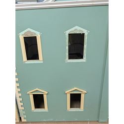 Two modern three storey dolls houses, each painted green with decorated interiors, both upon a single white wooden base, together with a large collection of dolls house furniture, accessories and figures 