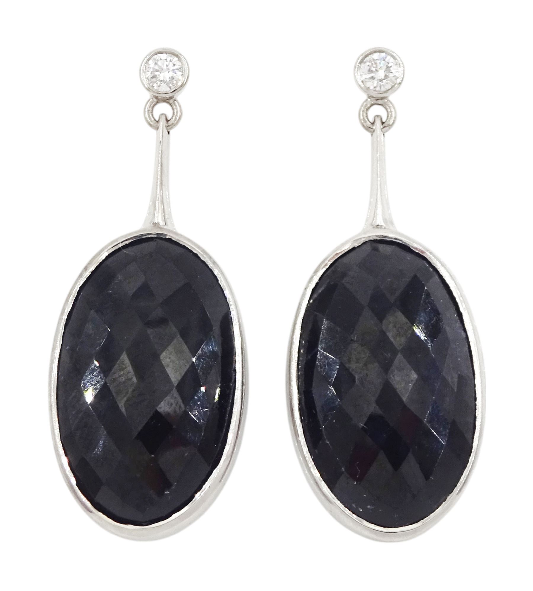 Pair of 18ct white gold sapphire and diamond pendant earrings, each stud set with a single round brilliant cut diamond, suspending an oval harlequin cut sapphire, hallmarked, total sapphire weight approx 31.30 carat