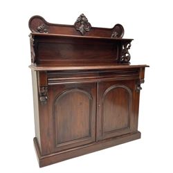 Victorian mahogany chiffonier, raised shaped back with foliage scroll carved mounts, on fretwork and carved bracket supports, moulded rectangular top over two frieze drawers and double panelled cupboard, on moulded plinth base