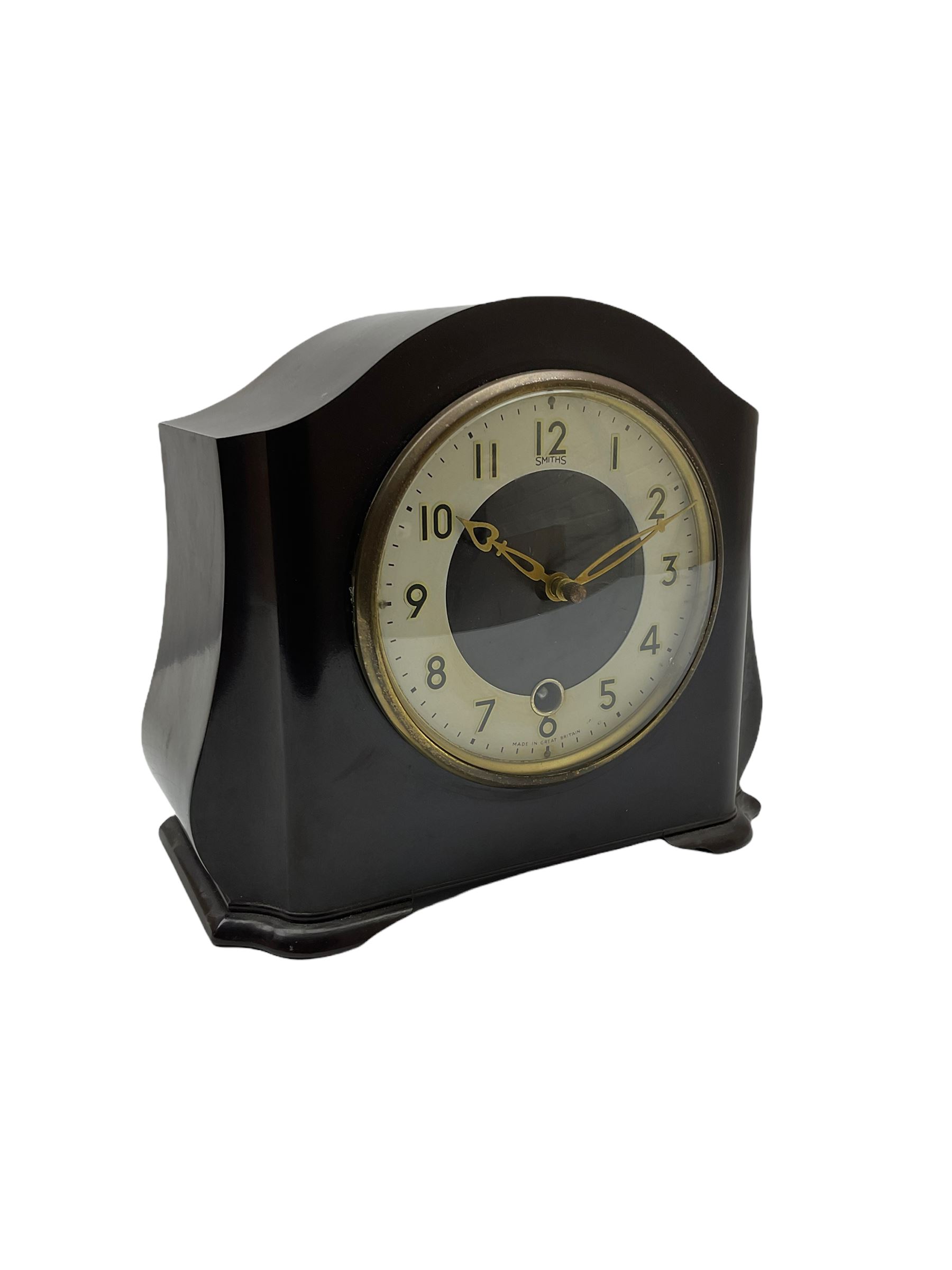 A Retro Art-Deco 1950's Bakelite cased mantel clock with a Smiths timepiece movement housed in a domed top case with curved sides on raised feet, dial with a cream chapter ring, upright Arabic numerals and minute markers, inscribed “Smiths, Made in Great Britain”, dial enclosed within a spun brass bezel and a convex glass, gilt pierced hands, spring driven 8-day pendulum movement. 
With pendulum.
