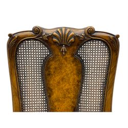 Pair of early 20th century Queen Anne design chairs, the cresting rail carved with scroll and central shell motif, shaped uprights and splat encased in cane work panels, shaped moulded seat frame with shell motif, floral needlework upholstered drop-in seat cushion, on shell carved cabriole supports with ball and claw feet, united by turned and shaped middle stretcher carved with acanthus leaf