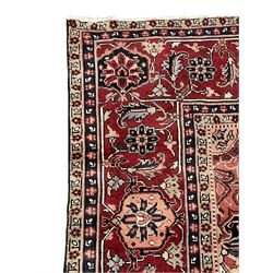 Persian Heriz dark indigo and red ground carpet, the central medallion with large projecting palmette motifs, overall floral design decorated with stylised plant motifs, repeating patterned border within guard stripes