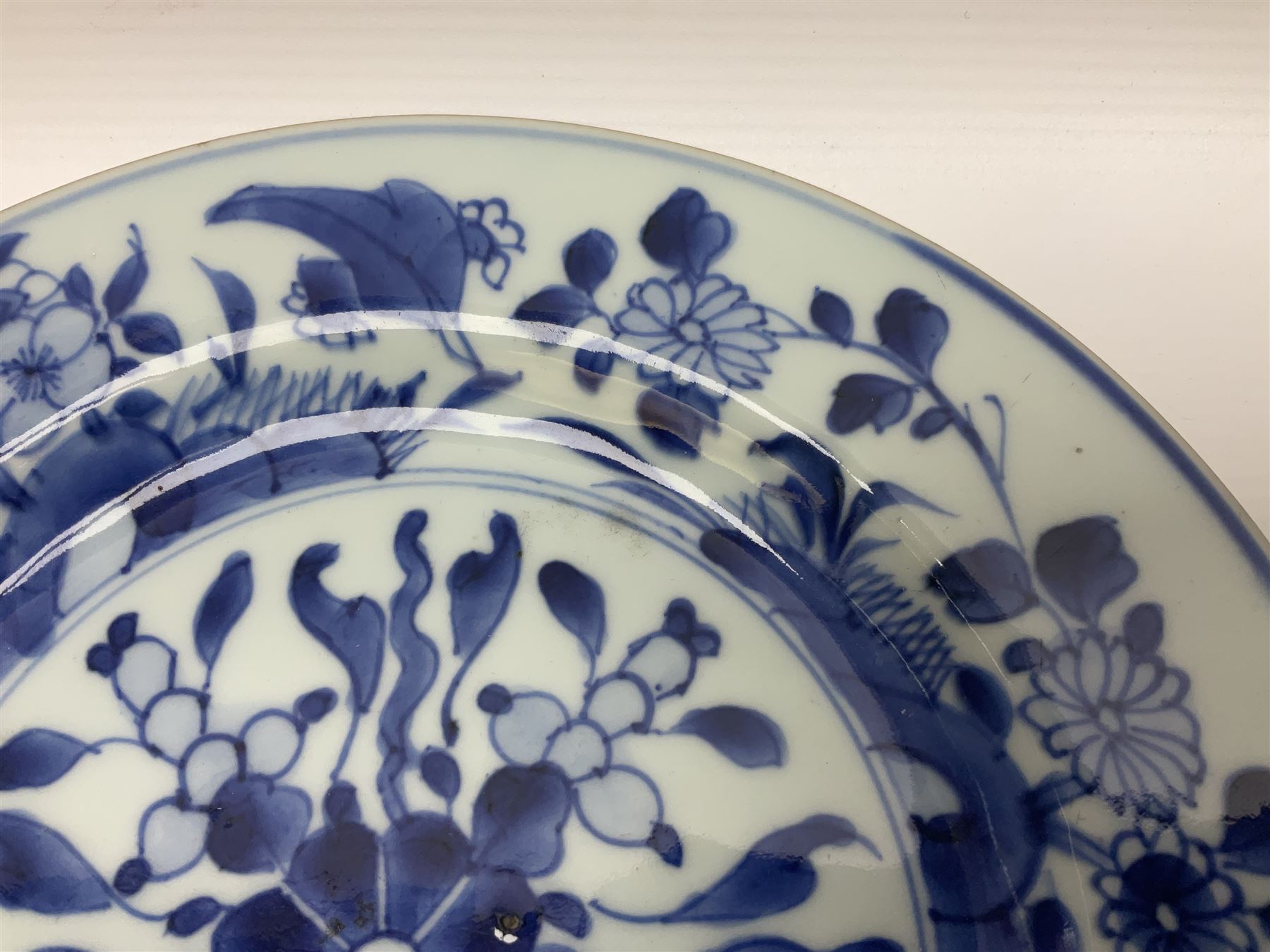 Japanese Meiji period Arita blue and white plate, of circular form, painted with riverside landscape and bird upon flowering branch, with character mark beneath, D24.5cm, together with two 18th century Chinese blue and white plates, each painted with floral design, each approximately D22.5cm