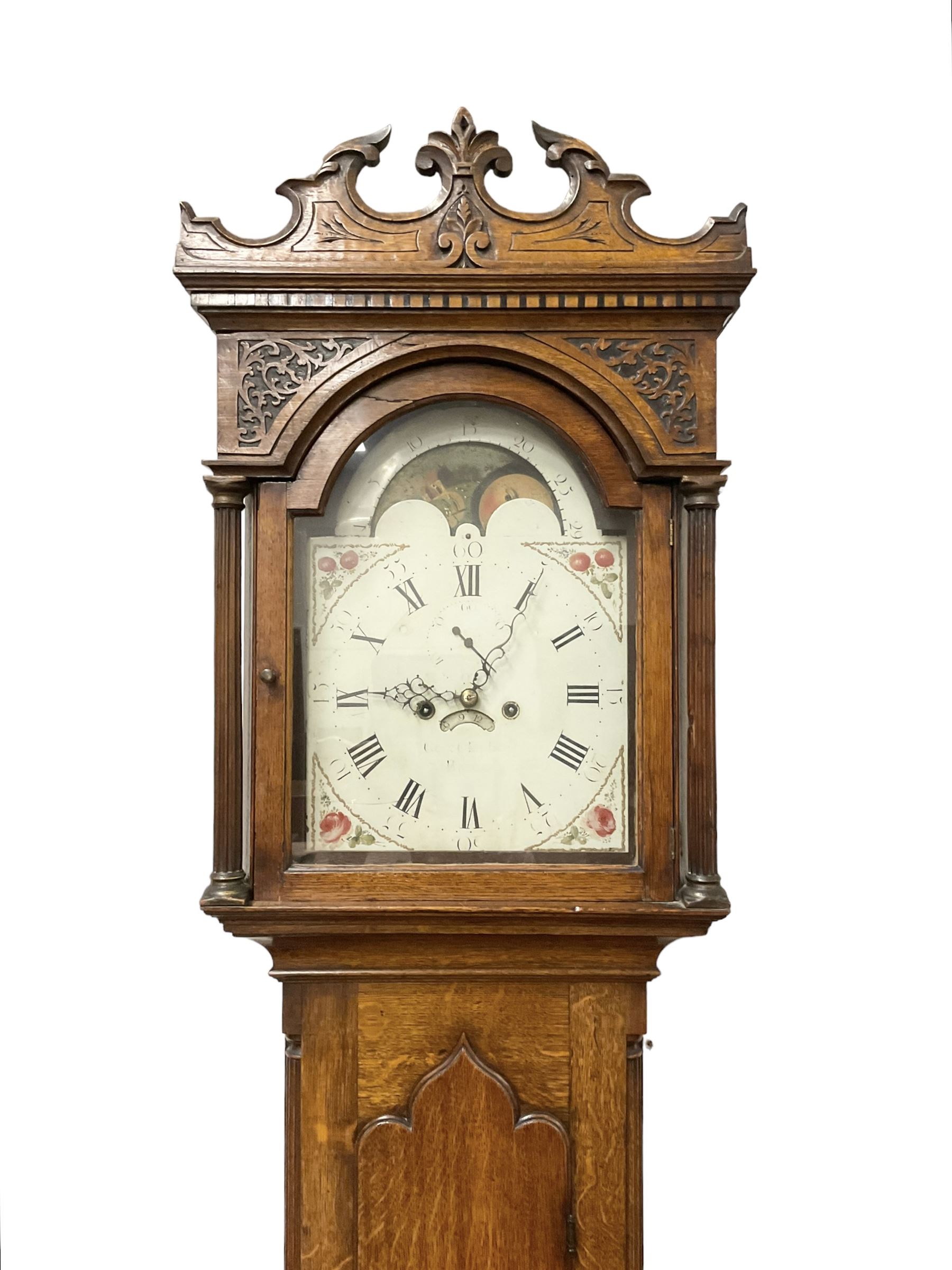 George Clapham of Brigg - Late 18th century 8-day oak cased longcase clock c1790 - flat topped hood with later carved addition, dog tooth moulding and blind fretwork beneath, break arch hood door flanked by reeded pilasters and capitals, trunk with canted corners and  door with a triple arched top, plinth with a later base with decoratively shaped feet, early painted dial with flowers enclosed in a gesso border to the spandrels, rolling moon to the arch, seconds dial and calendar aperture, Roman numerals and five minute Arabic's with makers name (indistinct), dial pinned via a false plate to a rack striking movement. With weights, key and pendulum.