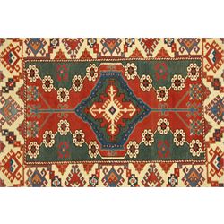 Caucasian Soumak rug, red madder field and teal panels, with bold stepped diamond medallion with hooked motifs and cruciform devices, and floral rosette clusters, surrounded by an ivory border with large hooked diamonds and stylized ram's horn devices, flanked by narrow guard stripes




