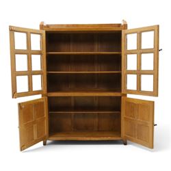 Rabbitman - oak glazed bookcase or display cabinet, lightly adzed rectangular top with raised gallery, twin glazed doors enclosing two shelves, over a pair of panelled cabinet doors with wrought iron fittings, with carved rabbit signature, by Peter Heap of Wetwang