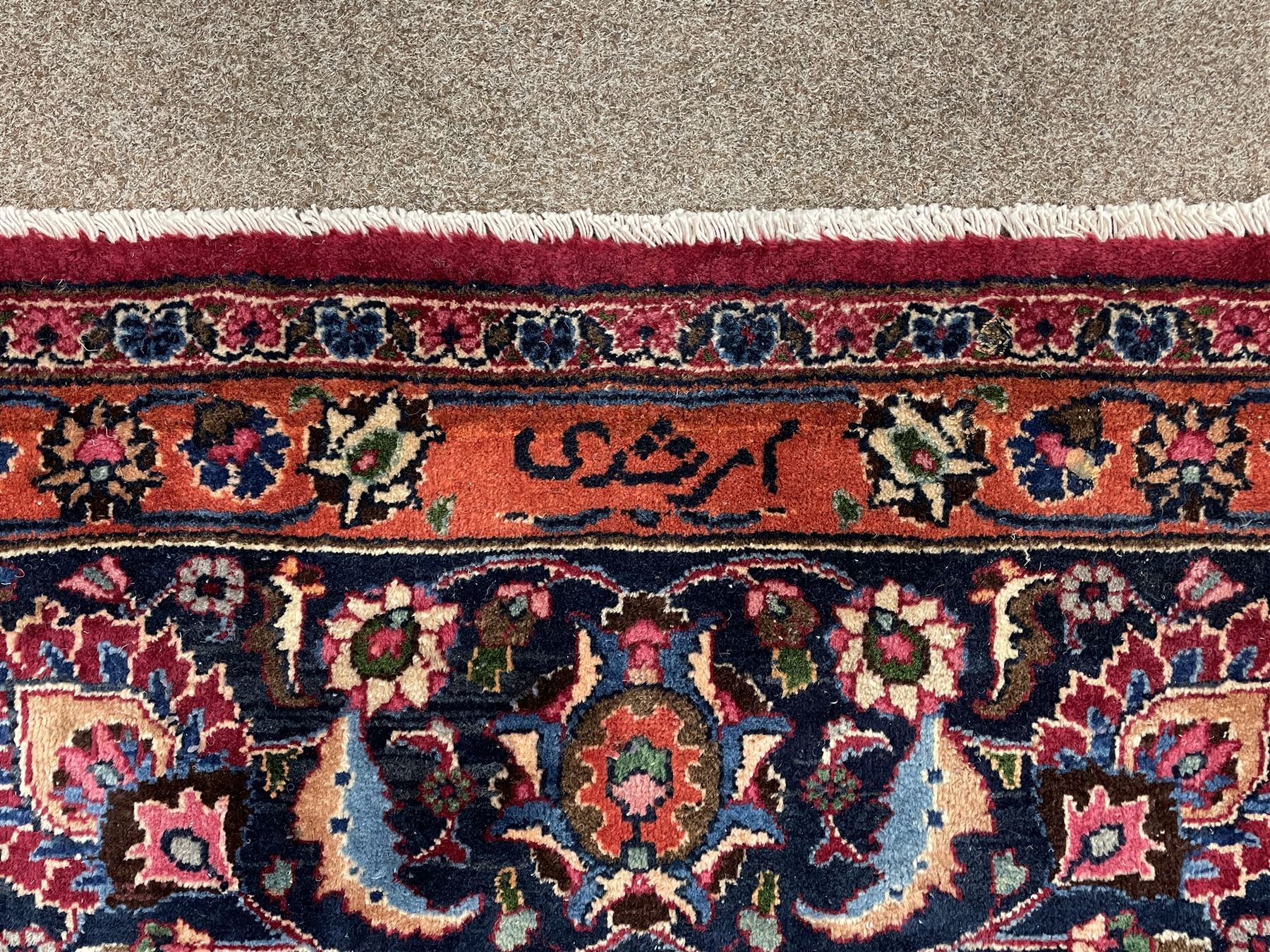 Persian Meshed carpet, plum ground and decorated with stylised flower heads and interlacing foliate, large central stylised medallion with orange detail, the orange mirrored in the five band border decorated with scrolling floral design, signature panel to end 