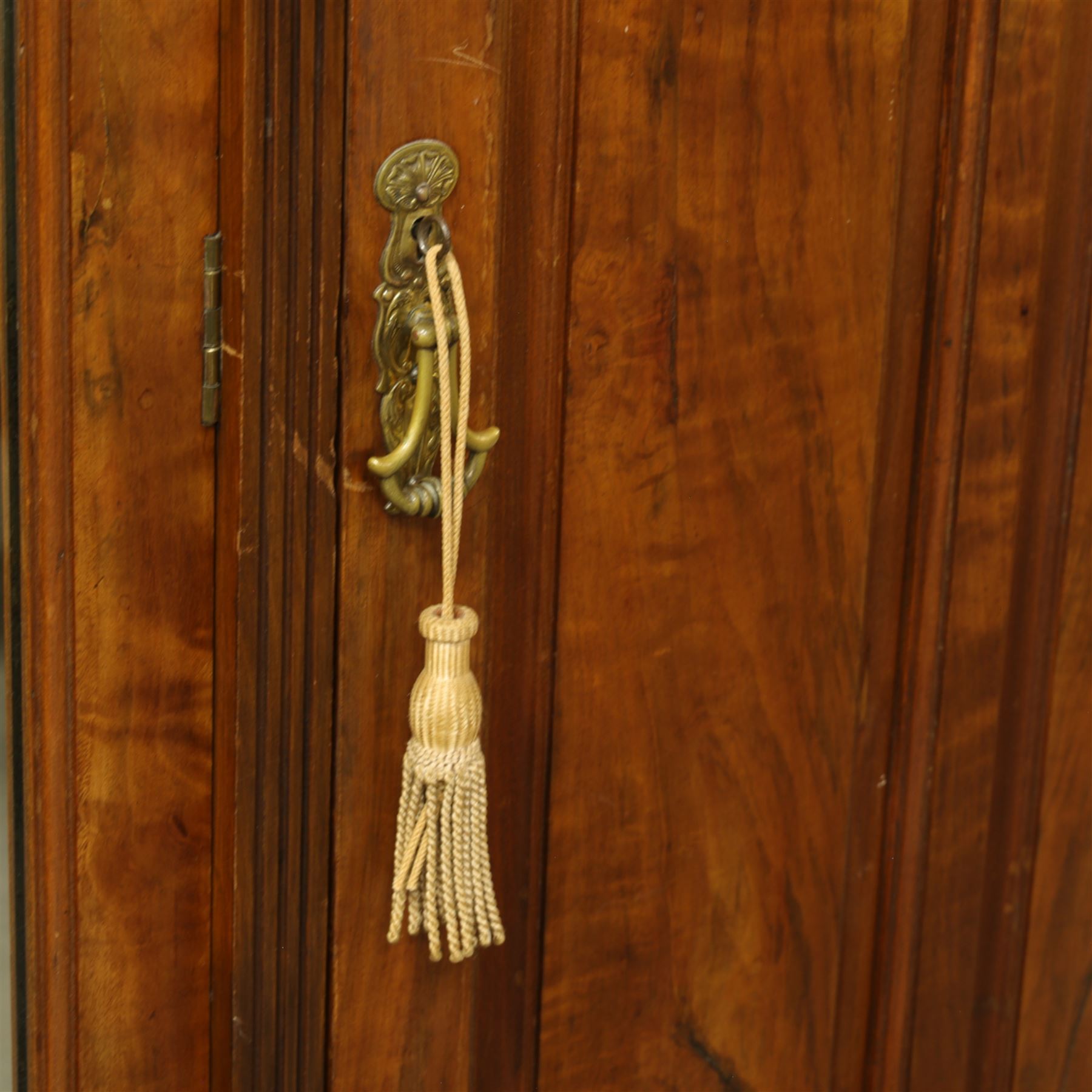 Edwardian walnut triple wardrobe, shaped broken-arch pediment over three doors comprising central mirrored door flanked by moulded raised and fielded panelled doors, interior fitted with hanging space and a bank of three open drawers above three brass recessed-pull drawers, on moulded plinth base