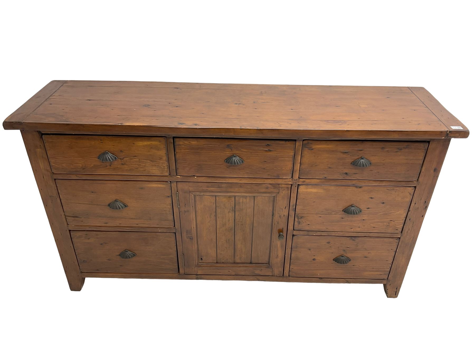 Stained pine rustic sideboard, rectangular top over seven drawers and single panelled cupboard, fitted with shell handles