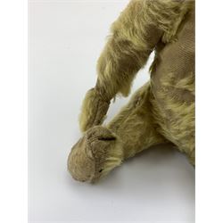 Early 20th century English teddy bear, with wood wool filled body with jointed limbs, felt covered paw pads, five claw stitching to feet and elongated arms with spoon shaped paws H14