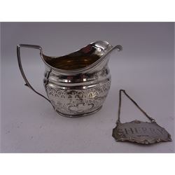 George III silver cream jug, of helmet form with angular handle, embossed with floral and scrolling decoration and engraved initial, hallmarked Edward Mayfield, London 1806, H9.3cm, together with a modern silver 'Sherry' decanter label, hallmarked Birmingham Mint, Birmingham 1986