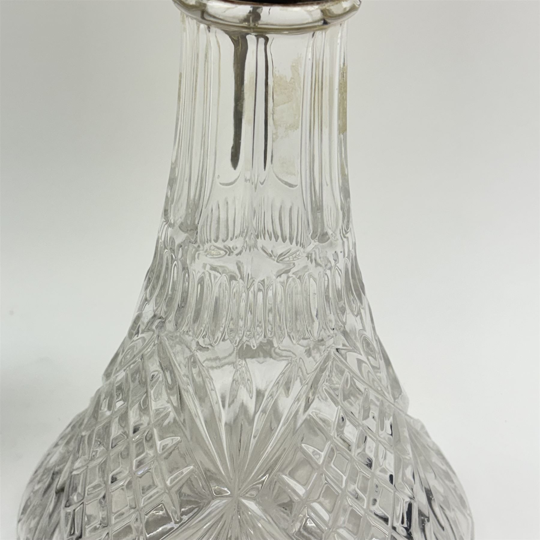 Silver plate mounted glass claret jug, the glass body of tapering form, the hinged lid a lion finial with shield shaped empty cartouche, the collar and spout cast with Bacchus face masks surrounded by grapes and vines, together with another silver plate mounted example, tallest H33cm