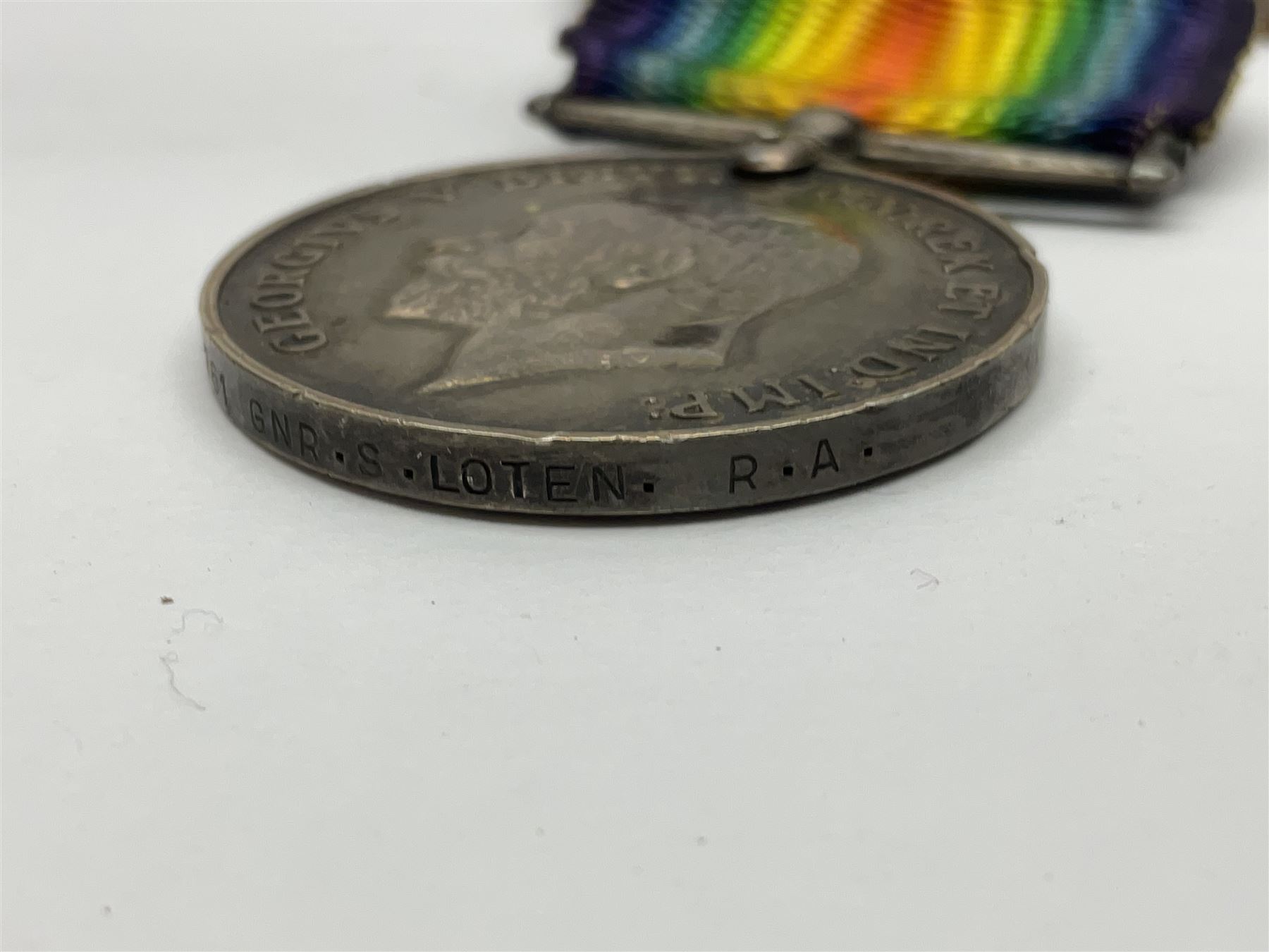 WW1 pair of medals awarded to 151761 Gnr. S. Loten R.A. with ribbons; four WW2 medals with ribbons; and small quantity of cap badges, medallions etc