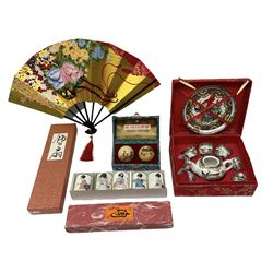 Quantity of boxed oriental collectibles to include sake cups, tea set, painted Chinese balls and fan (4)