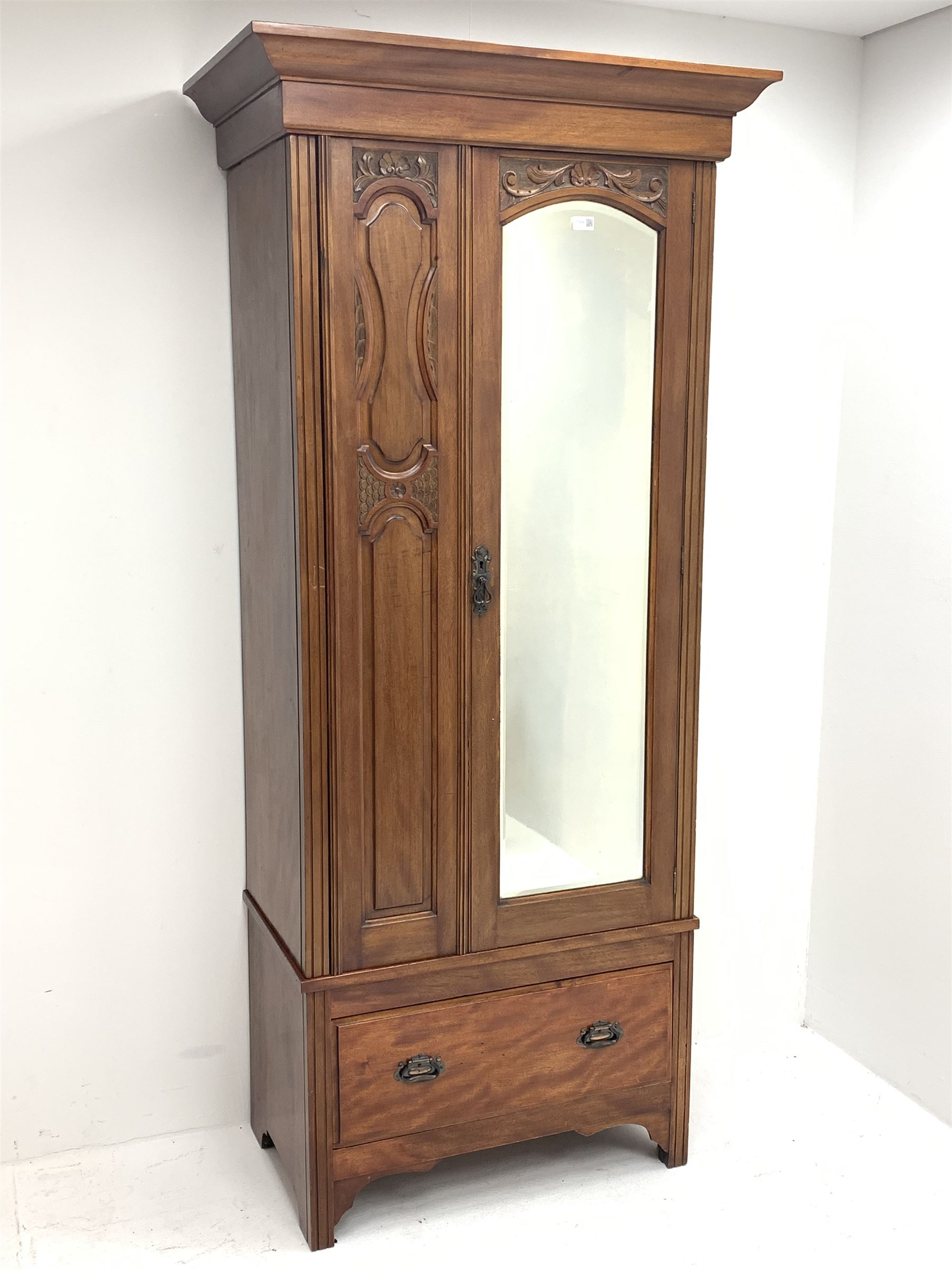 *Edwardian walnut narrow single wardrobe, projecting cornice over single bevelled mirror glazed door, panelled front carved with shells and flower heads, base fitted with single drawer, W90cm, H202cm, D54cm