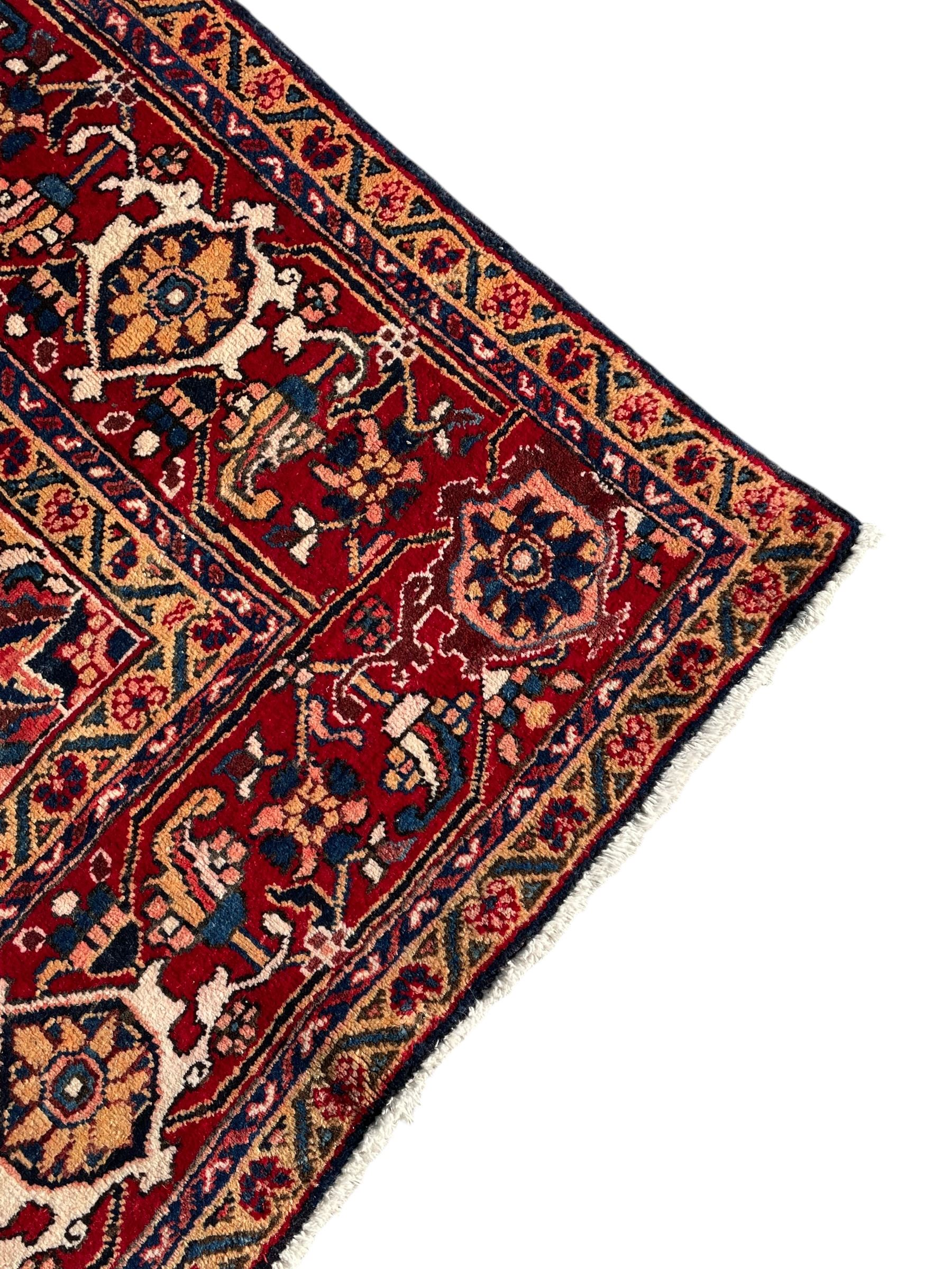 Persian Hamadan indigo and red ground carpet, large central medallion decorated with projecting palmette motifs, the surrounding field decorated with trailing branches and flower heads, crimson ground border decorated with stylised plant motifs, within floral pattern guard stripes 
