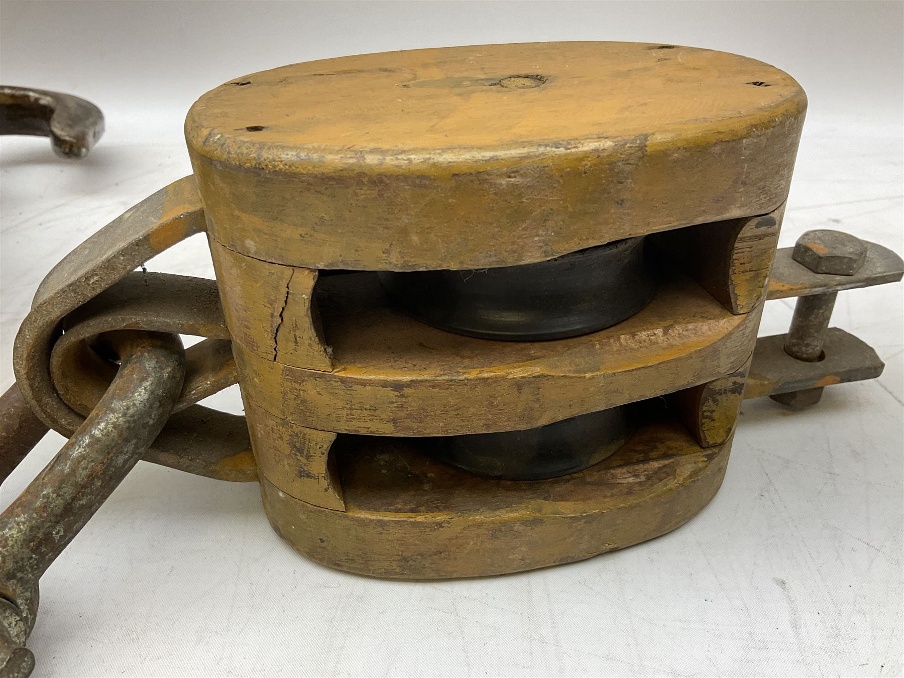 Three ship pulleys comprising wooden block double with swivel eye marked 'wooden block 240mm double rope: 22mm',  wooden block double with upset shackle and wooden block with stiff swivel hook, largest example L50cm