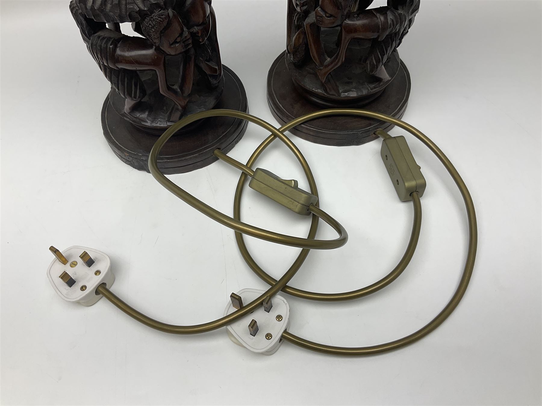 Pair of 20th century carved wood table lamp with African busts and figures, together with a carved wooden figure and soapstone figure, lamps H44cm