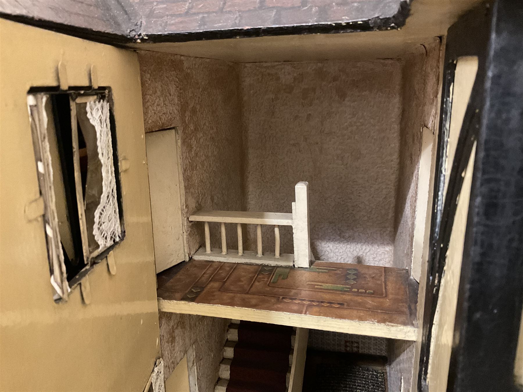 Large Tri-ang No.93 doll`s house in the 'Stockbroker's Range' c1935; two-storey double-fronted Tudor design, half timbered gables, two-storey bay windows, cream and mock shrubbery to front, opening metal framed windows with green shutters, red simulated tiled roof with chimney, integral garage with opening doors, front elevation has four hinged doors opening to reveal two bedrooms with fire places, living room, bathroom and kitchen with built in dresser and sink, entrance hall and staircase, side entrance with porch and seat and sun dial over on chimney stack; some wiring for electrical lighting; metal Tri-ang Toys disc verso; comprehensively furnished H66cm L117cm D43cm