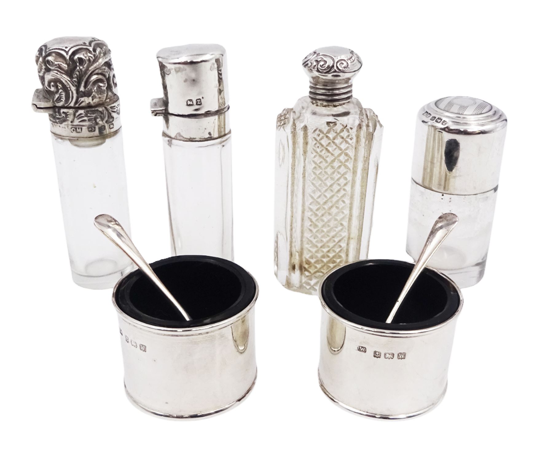Four silver mounted glass scent bottles, including a Victorian cut glass example with embossed silver cover, and three cylindrical plain glass examples, on with engine turned decoration, three with glass stoppers, together with a pair of silver salts and spoons, all hallmarked, tallest H8cm