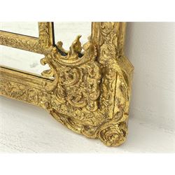 Large Victorian style gilt cushion framed mirror, putti holding urn with scrolled foliage pediment above central rectangular bevelled plate, the frame decorated with moulded foliate, each corner set with ornate cartouche
