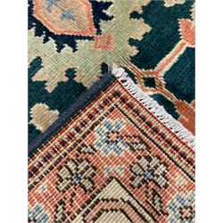 Persian emerald green ground rug, the field decorated with large stylised plant motifs, ivory ground border with repeating leaf motifs, the guards decorated with trailing branch and flowerhead motifs