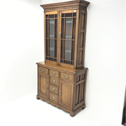 Edwardian oak bookcase on cupboard, two stained glass doors enclosing three shelves above six drawers and two cupboards, shaped plinth base, W106cm, H205cm, D44cm