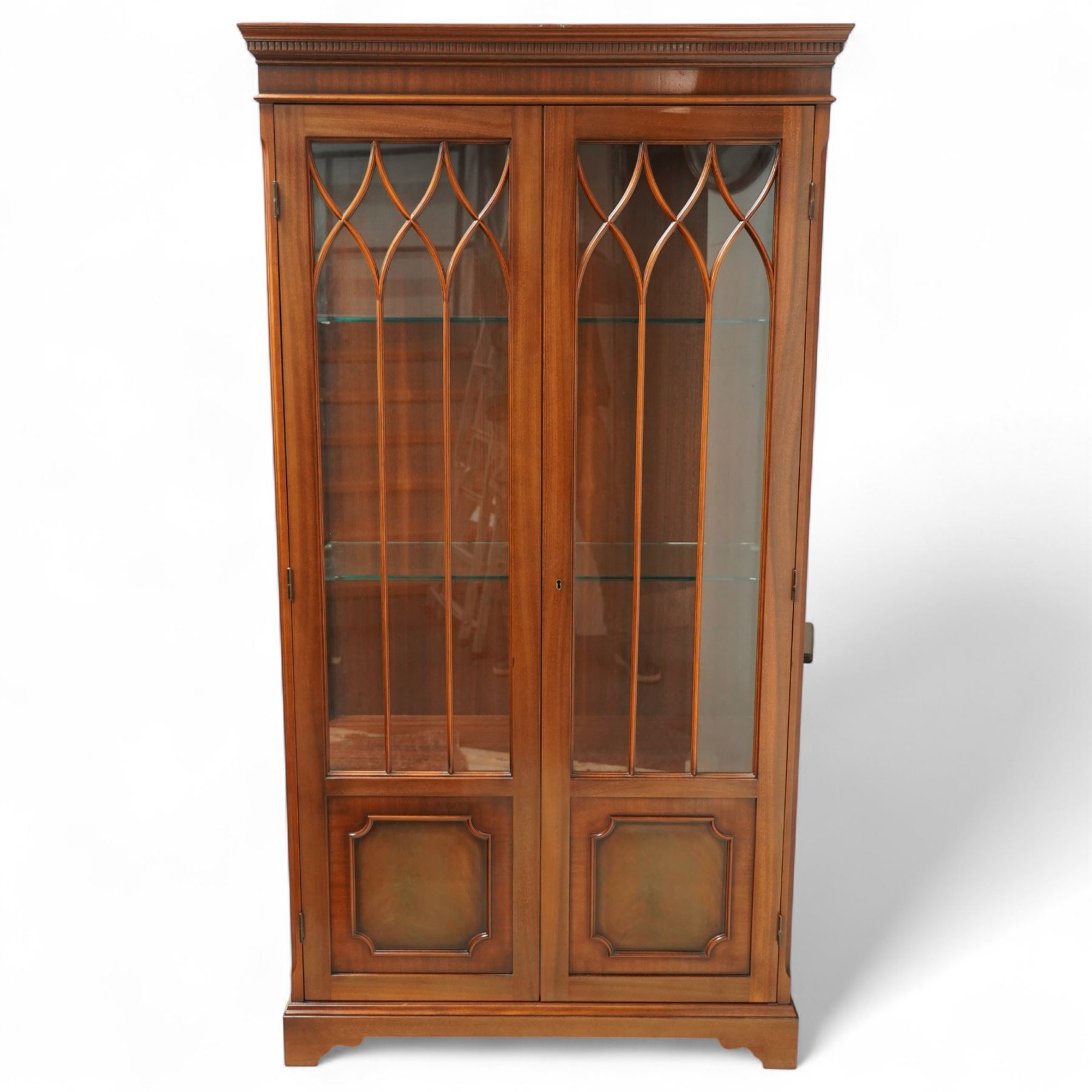 20th century Georgian design mahogany display cabinet with illuminated interior, dentil moulded cornice over twin astragal glazed doors enclosing glass shelves, lower panelled cupboard doors, on shaped bracket feet