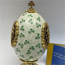 Franklin Mint The Emerald Isle Collector Egg, the egg decorated with embossed shamrocks upon a cream ground, with a gilded shamrock finial, accents and openwork door, opening to reveal a miniature landscape scene, upon three gilded feet set with green paste stones, with certificate of authenticity H23cm, 