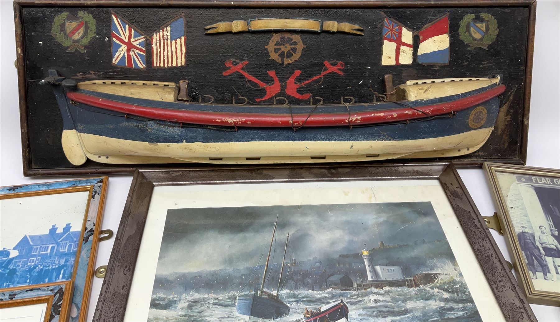 RNLI collection box in the form of a boat makers half block model, painted in the colours of a lifeboat with flag and ship motifs, H25cm, L73cm together with framed photos, postcards and prints of lifeboats and crew, including Scarborough lifeboat station