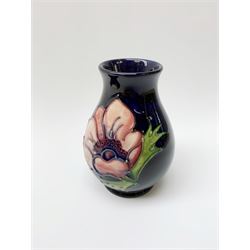 A Moorcroft pin dish and small vase, each decorated in the Anemone pattern upon a dark blue ground, each with impressed marks beneath, pin dish D11.5cm, vase H10cm.
