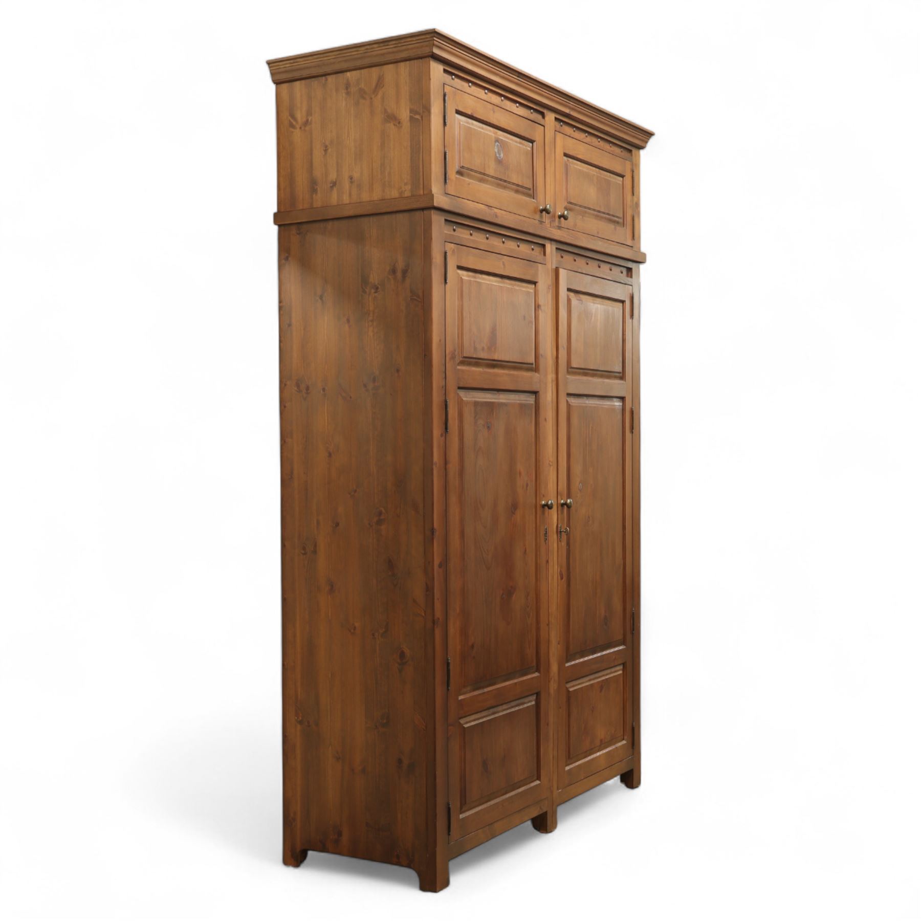 Traditional design contemporary dark stained pine double wardrobe with top box, twin three panelled door with wooden studded frieze, enclosing a single metal rail, with a top box above with brass handles