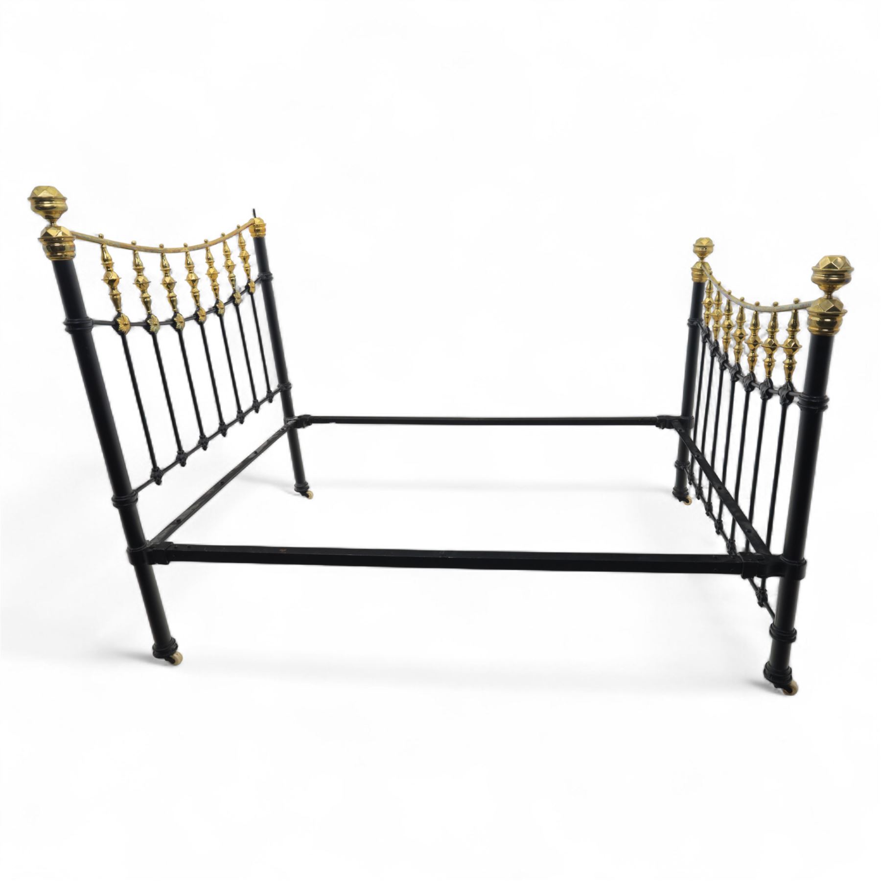 Victorian brass and iron 4' 6'' double bedstead, curved brass top rail with cast iron spindles and ornate floral rosettes flanked by urn shaped finials, foldable divan style base upholstered in a striped fabric, supported on turned posts and ceramic castors