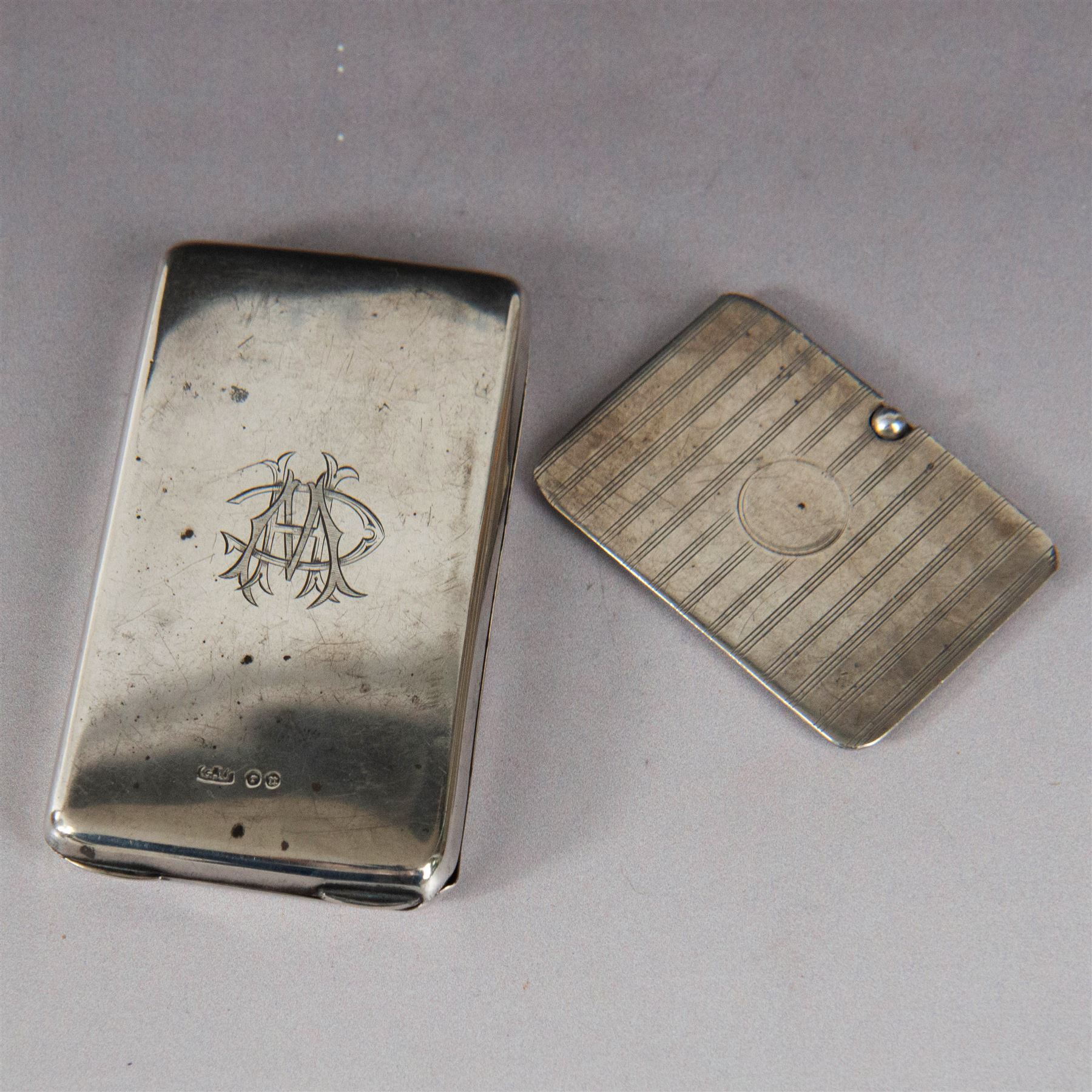 Two silver stamp cases, comprising Victorian silver mounted example with leather interior and engraved monogram to cover, hallmarked George Unite, Birmingham 1897, and a 1920s sliding example with engine turned decoration and vacant cartouche, hallmarked Sydney & Co, Birmingham 1924