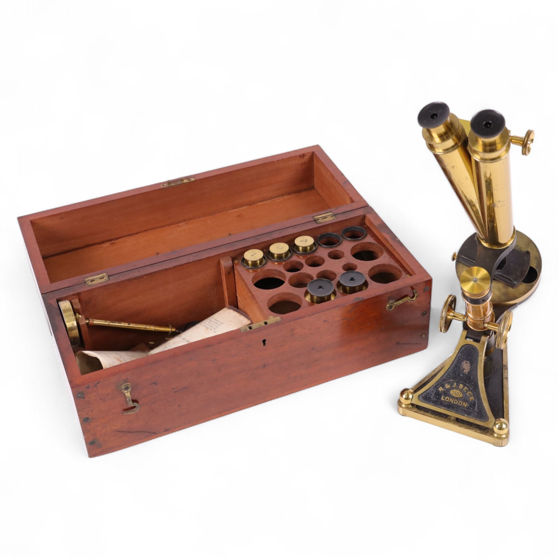 19th century brass binocular microscope by R&J Beck, London, numbered 5527, with rack and pinion focusing, with four eye pieces and three objective lenses, in wooden case