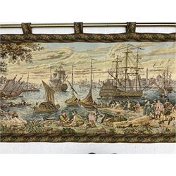 20th century tapestry style wall hanging depicting 17th century port scene, possibly Venice, the harbour filled with traders and merchants, together with a garden scene example depicting a waterfall and lake amongst flowers and trees, both with foliate borders, lined to reverse and suspended from brushed metal poles, largest approx W200cm