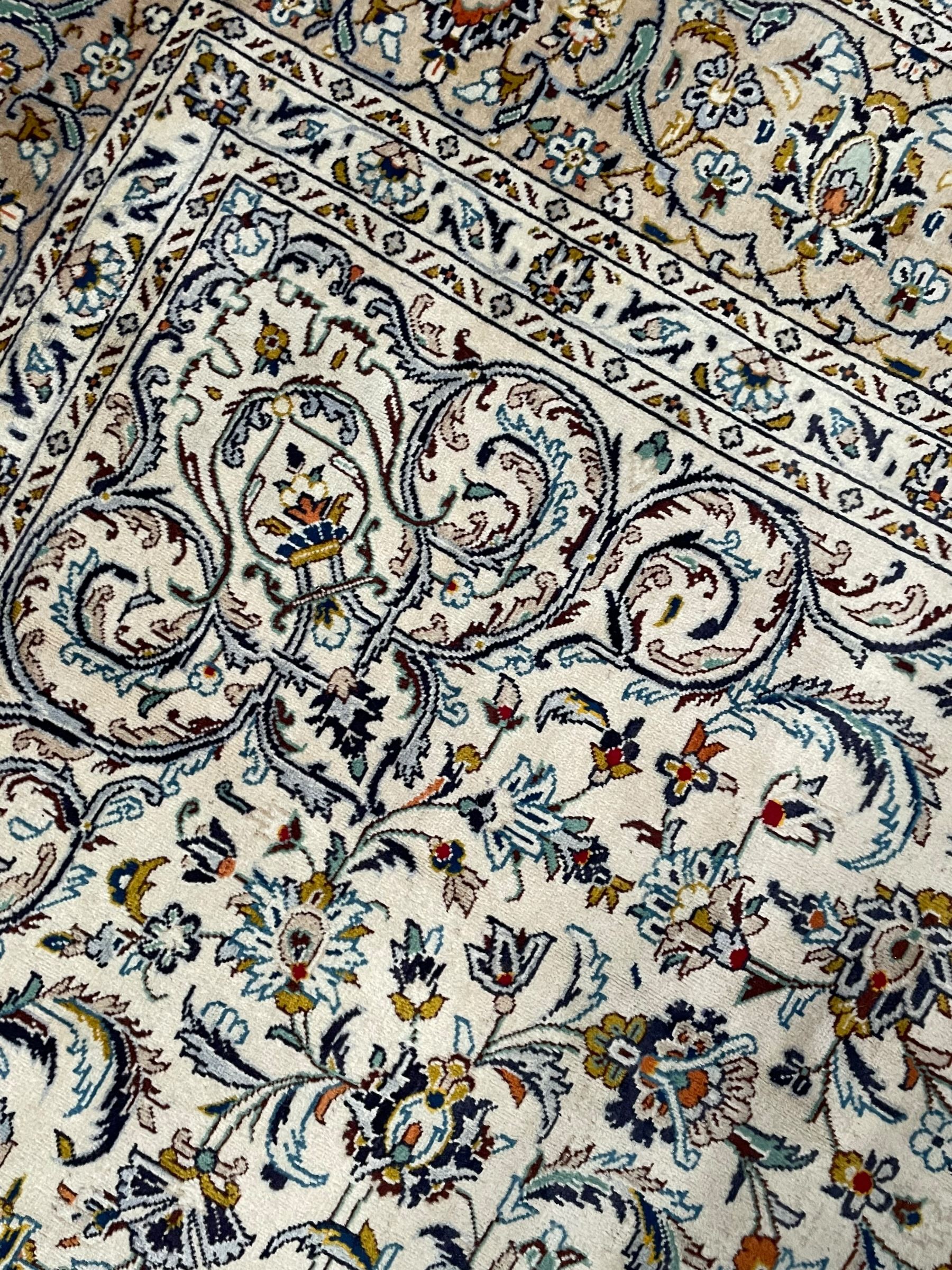 Persian Kashan ivory ground carpet, central pole medallion surrounded by swirling leafy branches and stylised plant motifs, scrolled foliate spandrels, the main border decorated with scrolling pattern and repeating palmettes, within floral patter guard stripes 