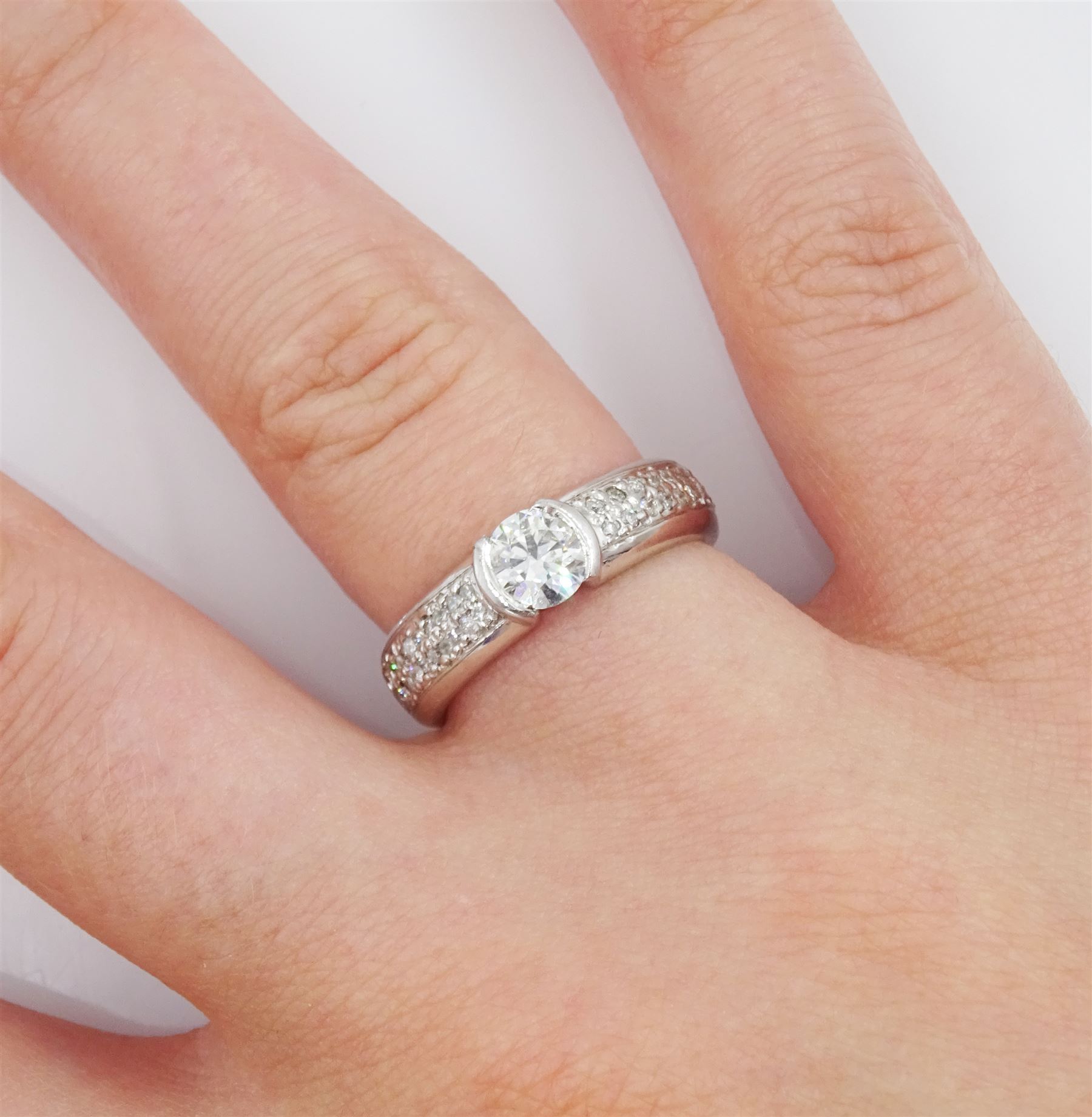 18ct white gold diamond ring, half bezel set with a single round brilliant cut diamond of approx 0.45 carat, with pave set round cut diamond shoulders, hallmarked