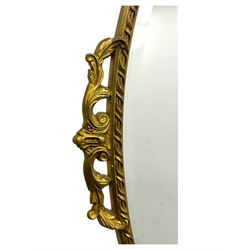 Oval gilt wall mirror, with bevelled edge plate within a moulded frame cast with acanthus scrolls and foliate decoration, pierced cartouche crest and apron, flanked by scrollwork handles