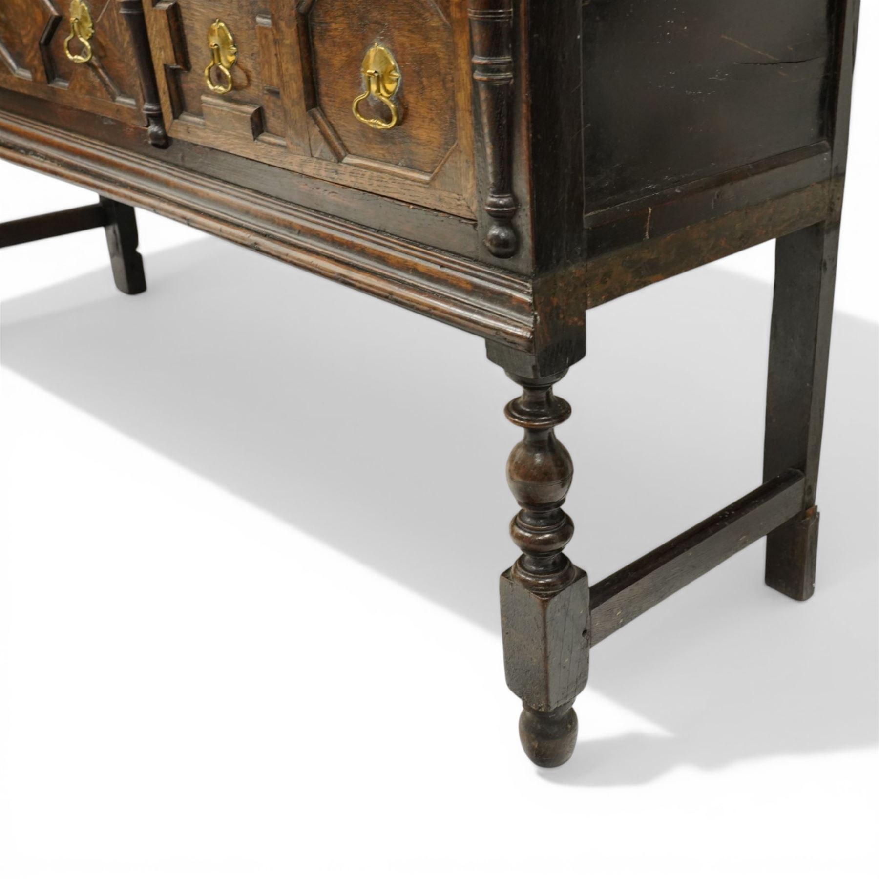 19th century Jacobean Revival oak dresser and rack, the upper section with open shelves and central cupboard, flanked by bobbin moulded uprights, the base fitted with three carved drawers with brass ring handles, raised on turned supports united by stretchers