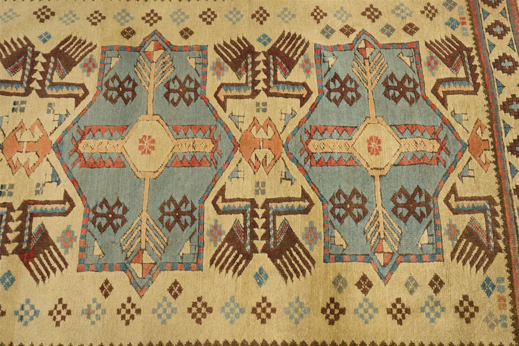 Two Caucasian designed rugs comprising a flatweave and hand-knotted rug, Caucasian design flatweave, cream ground with three large blue geometric medallions surrounded by stylised birds and geometric motifs, enclosed by repeating geometric border, fringed ends, H176cm, W102cm; hand-knotted Caucasian rug, ivory ground with three polychrome octagonal medallions surrounded by stylised animals, flowerheads and geometric motifs, enclosed by salmon pink geometric border, fringed ends, H163cm, W106cm