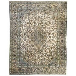  Central Persian Kashan pale khaki ground carpet, shaped central medallion enclosing small stylised motifs, the field decorated profusely with trailing foliate branches and plant motifs, guarded border with repeating floral design 