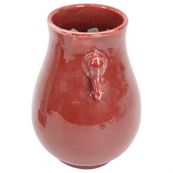 20th century Chinese sang de boeuf vase of baluster form with elephant head handles, togehter with a pair of famille rose vases decorated with floral decoration and insects, upon wooden stands   