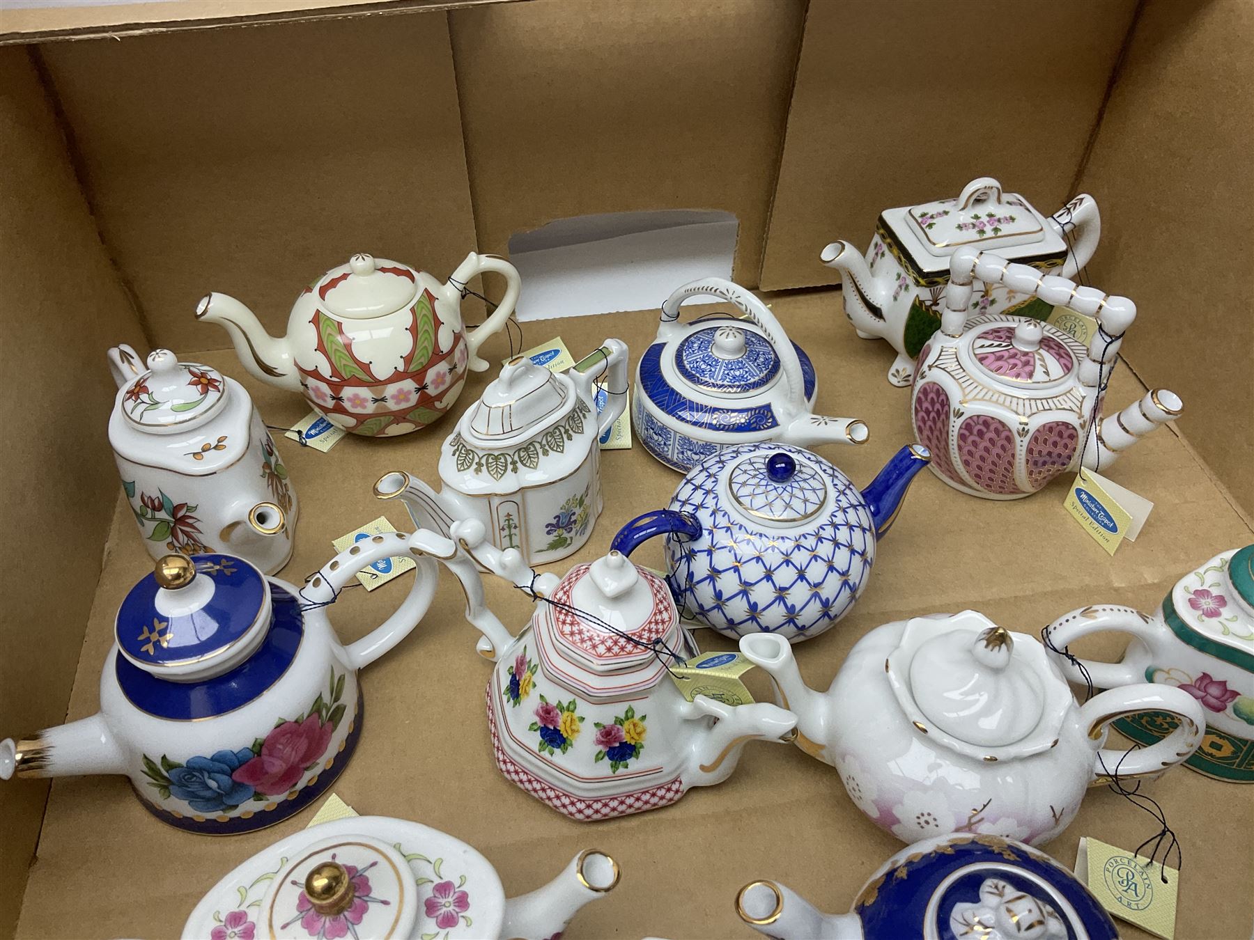 Twenty seven Porcelain Art miniature teapots, with wooden display together with a collection of other ceramics and glassware etc, including Goebel Hummel collectors plates, in three boxes,