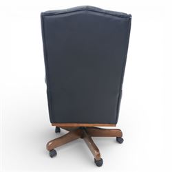 Chesterfield style desk chair upholstered in black, brass studded trim with tall button backed seat, with faux wooden base raised upon castors