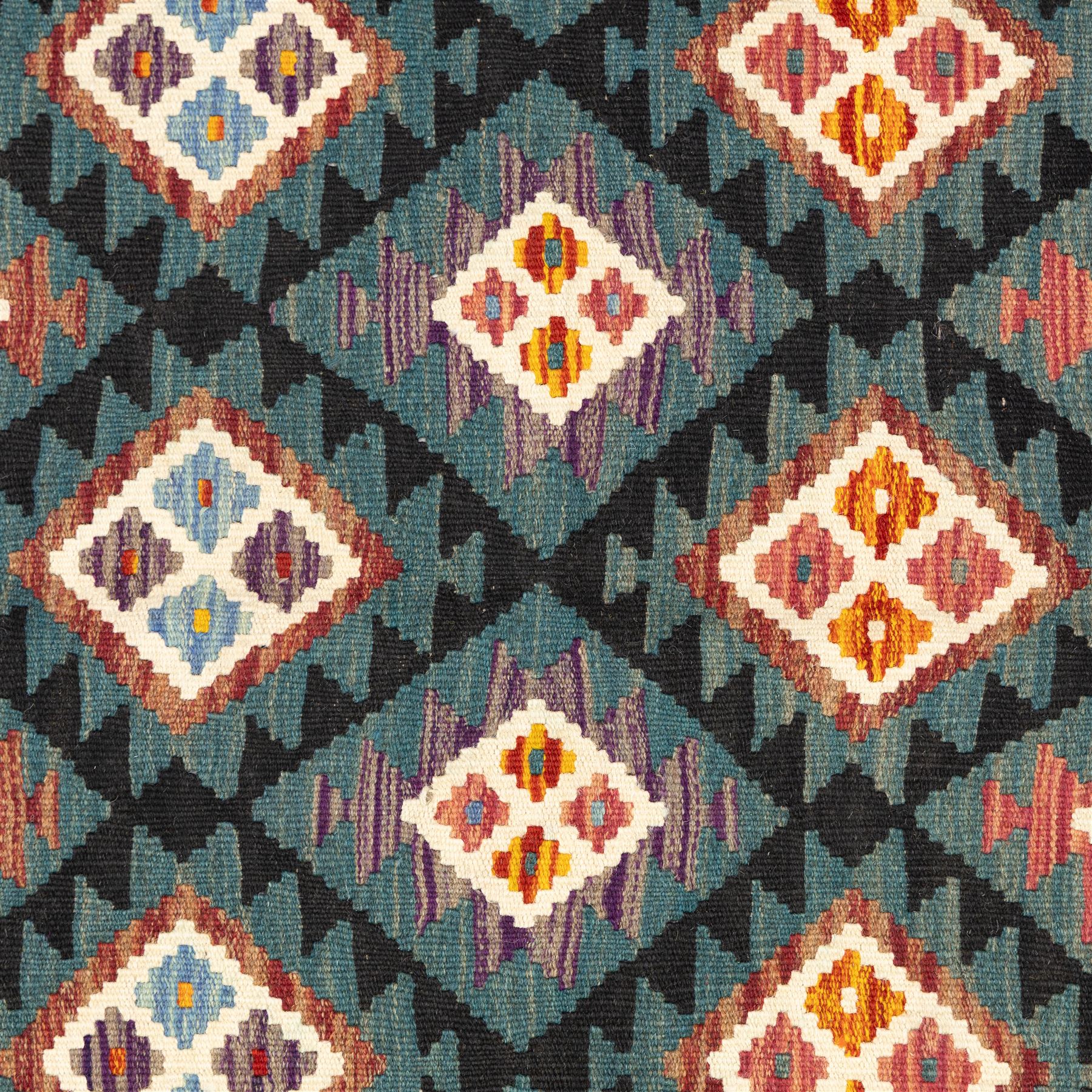 Chobi flatweave kilim with a repeating stepped diamond medallion design in live green, rust, teal, purple, and ivory, framed by chevron and geometric borders