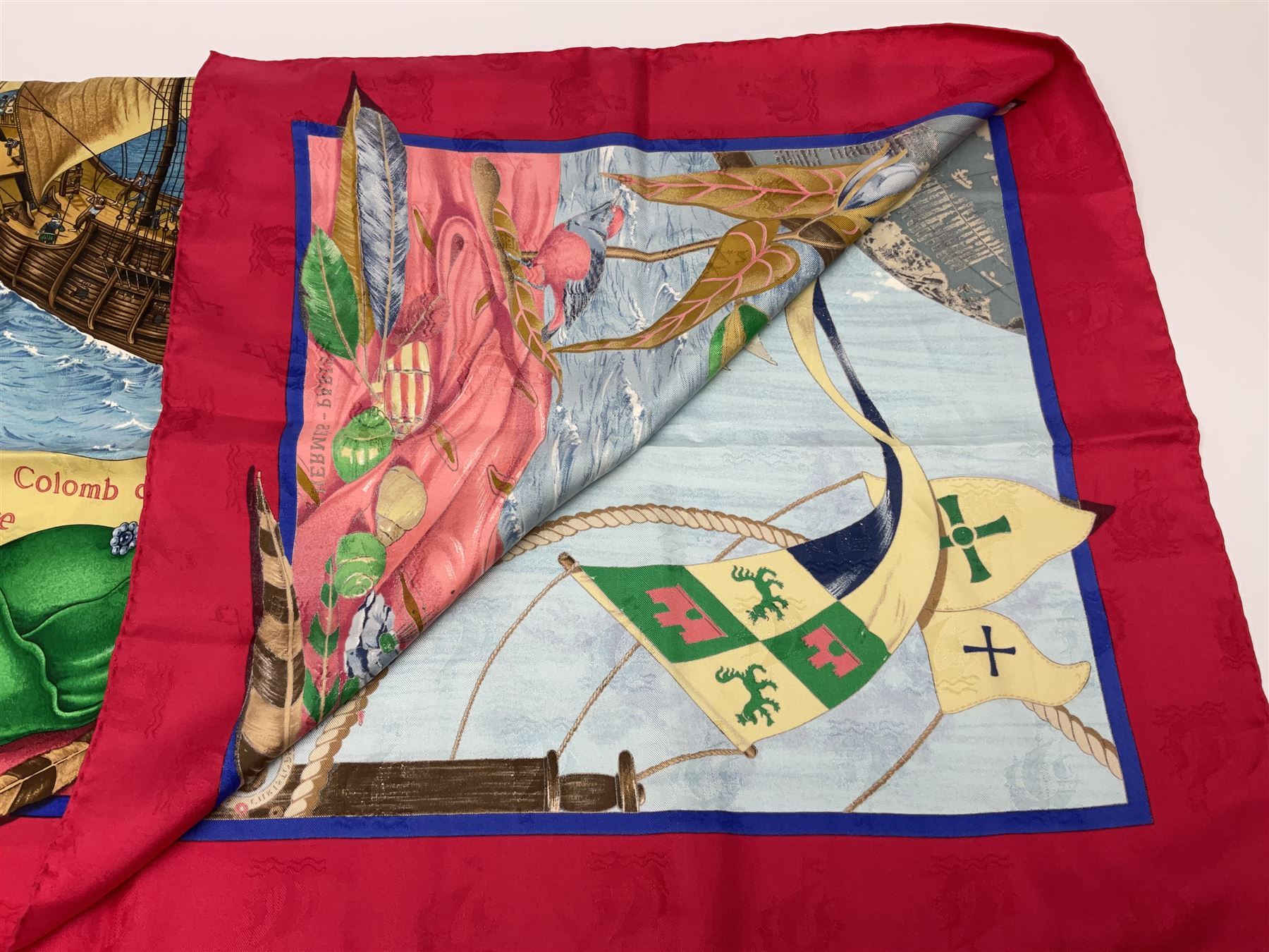 Hermès 'Christophe Colomb Découvre l'Amérique' jacquard silk scarf, designed by Carl de Parcevaux in 1992, limited edition for the bi-centenary of the discovery of America, printed with a central image of Christopher Columbus' ship at sea, surrounded with colourful stylised feathers, birds, flags, globes, shells and flowers, contained within vibrant red border, with rolled hand stitched edges and Hermes material label, 87cm square