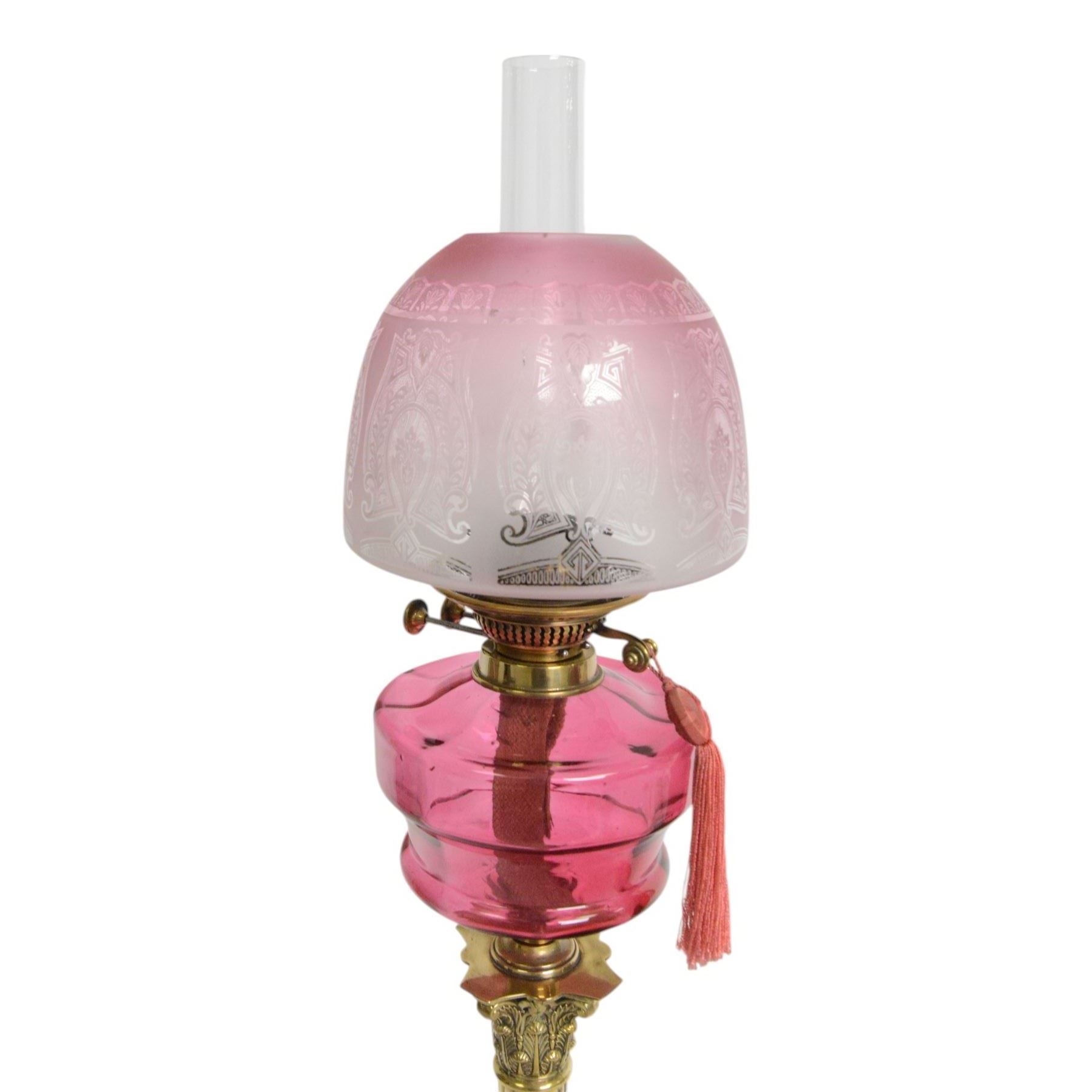 Victorian brass oil lamp, the Corinthian column supporting a cranberry glass burner and opaque etched cranberry glass shade and clear glass chimney, overall H77cm