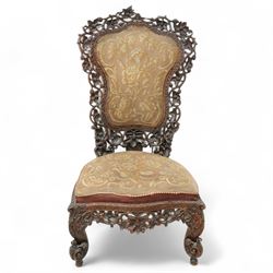 Late 19th century Anglo-Indian carved hardwood nursing chair, cartouche-shaped back, pierced fruit vine carved frame, gros-point tapestry upholstered seat, on carved scroll legs 